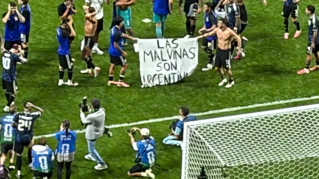 Bandera argentina con la leyenda Las Malvinas son argentinas exhibida por futbolistas