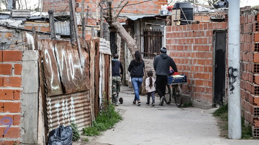Vista de un barrio popular con construcciones precarias y un estacionamiento que funciona como cancha de fútbol.