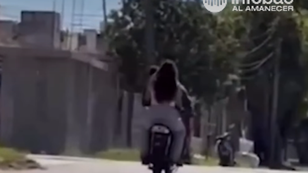 Pareja en moto realizando willy con un bebé en brazos
