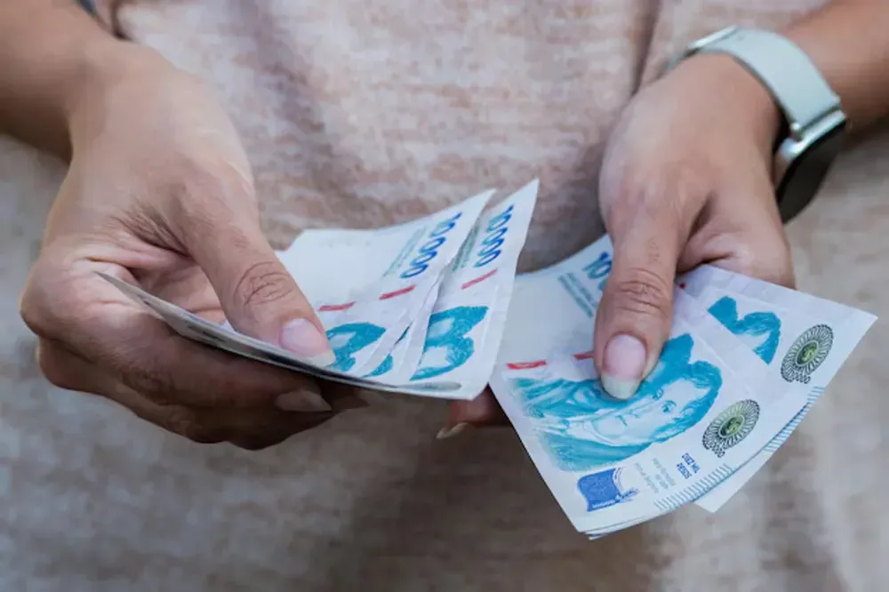 Personas trabajando en una oficina, con documentos y calculadora, en referencia al salario mínimo